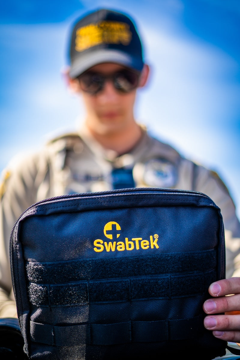 uniformed sheriff deputy holding swabtek narcotics test kit go bag