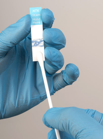 swabtek cocaine detection test kit in use by hands wearing blue gloves